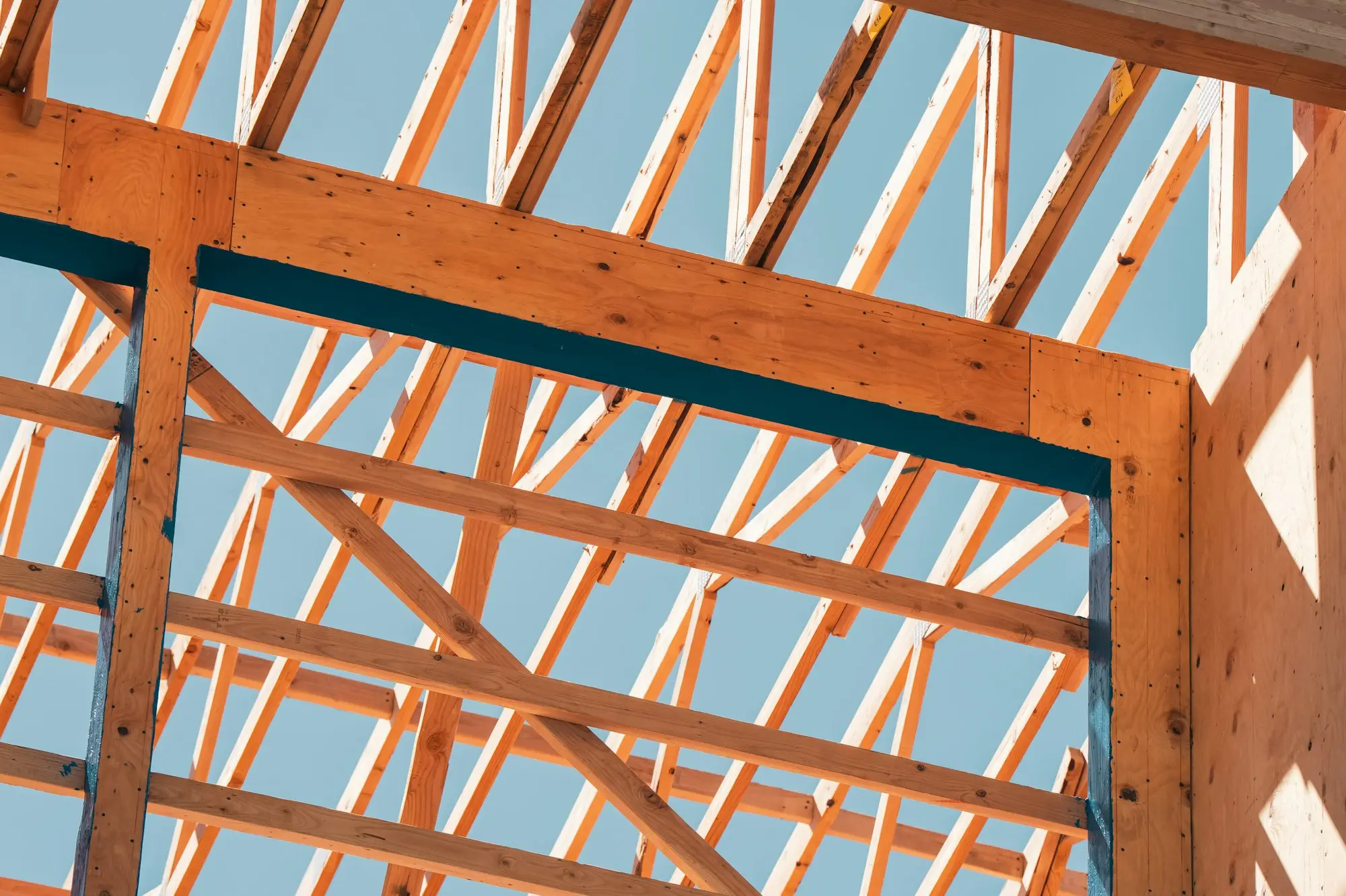Timber roof trusses on a new house frame against a blue sky