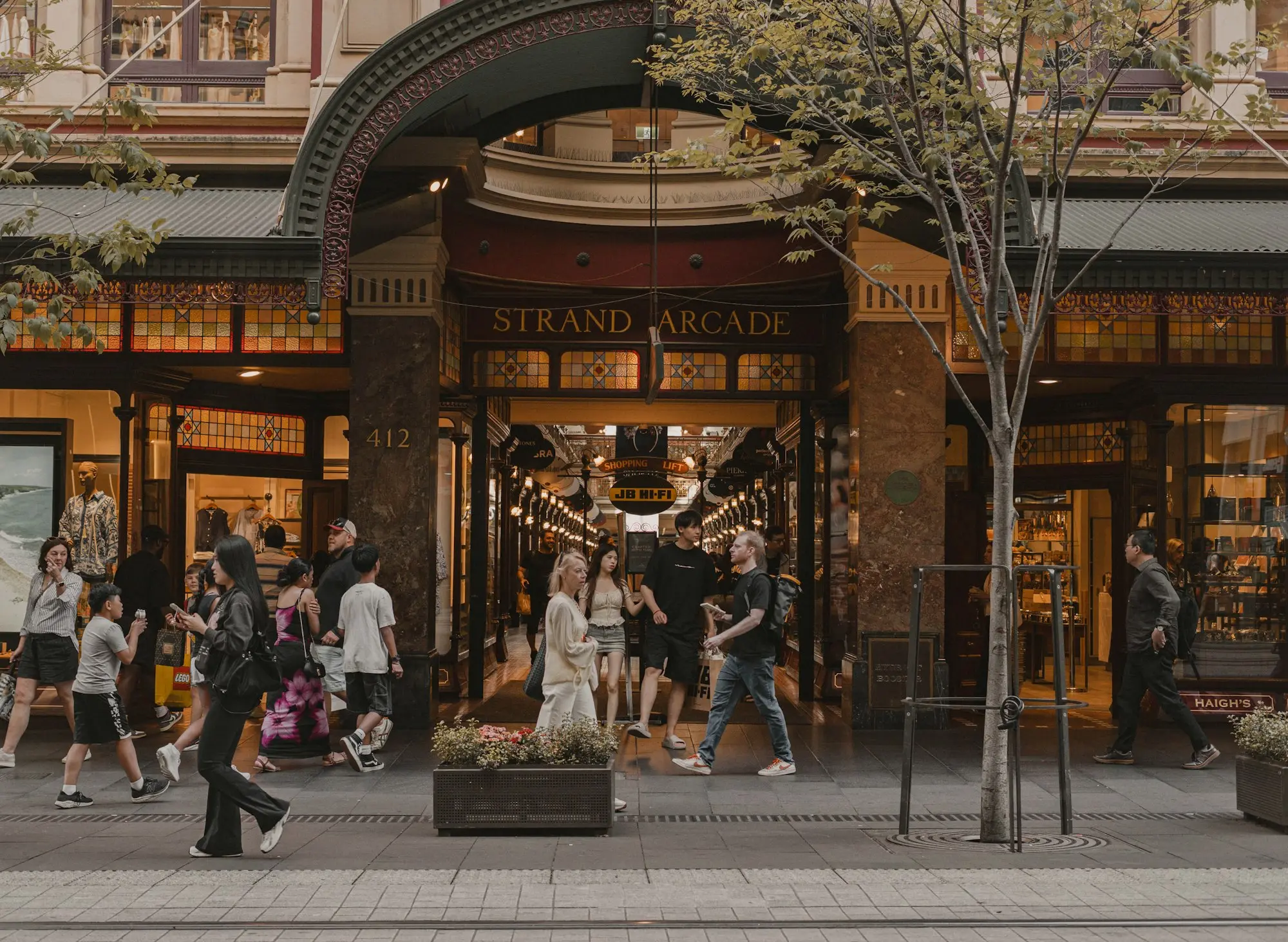 Shoppers walking past a heritage arcade entrance on a city street