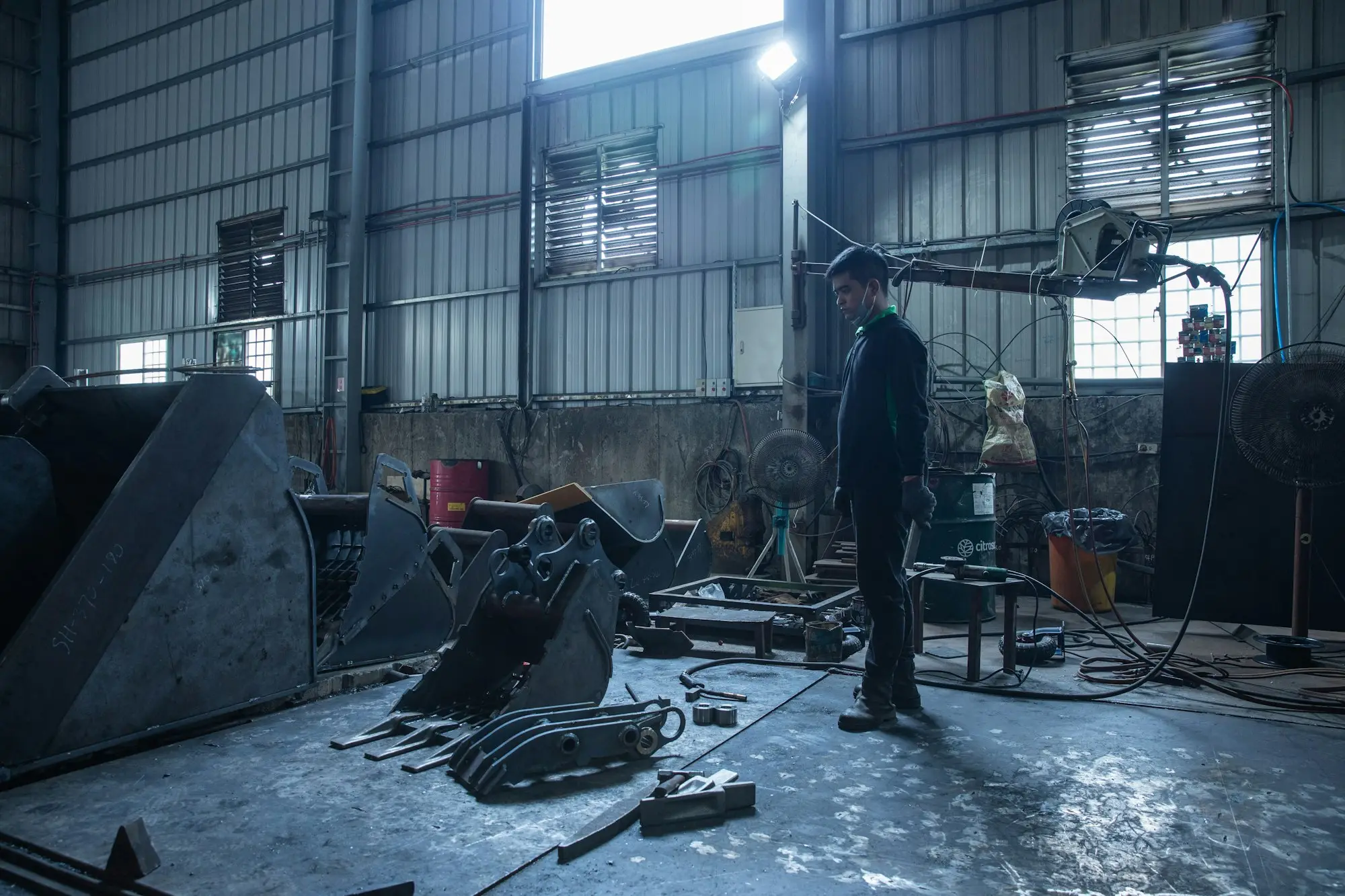 Owner standing in a busy metal workshop beside heavy machinery